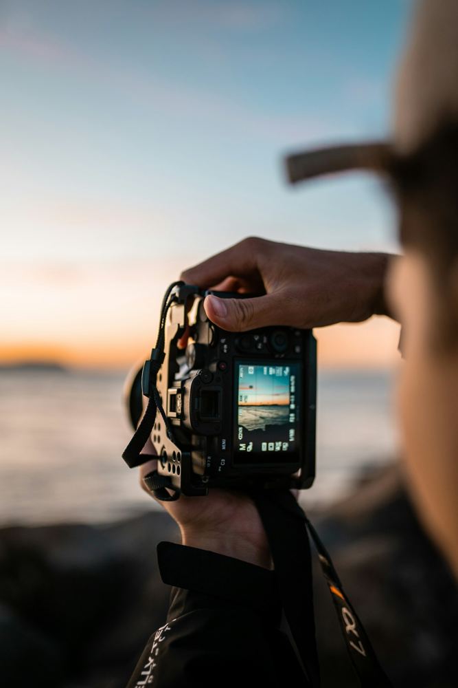 Gün batımında fotoğraf makinesiyle çekim yapan eller